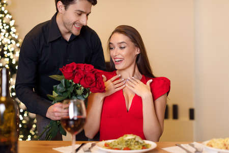 Young handsome man giving red roses to womanの写真素材