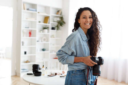 Female Photographer Posing Holding Photocamera Standing In Modern Studioの写真素材