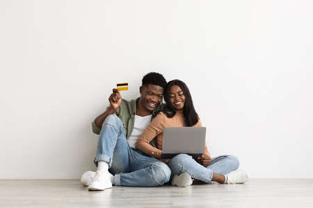 Cheerful african american couple using laptop and credit cardの写真素材