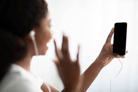 Black lady waving at smartphone with empty screenの写真素材