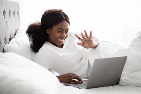 Cheerful african american woman having video chat, using laptop