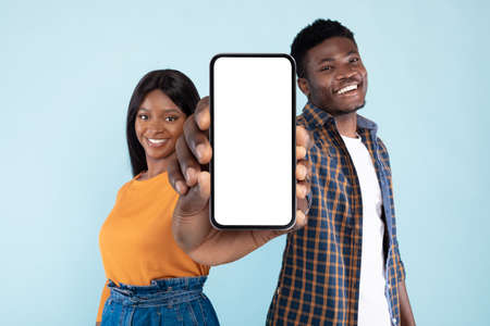 Black couple showing two blank empty smartphones screen for mockupの写真素材