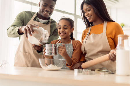 Black Family Using Flour Sifter Making Dough Baking In Kitchenの写真素材