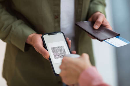 Unrecognizable Man Showing Vaccination Certificate On Phone Standing Indoorの写真素材