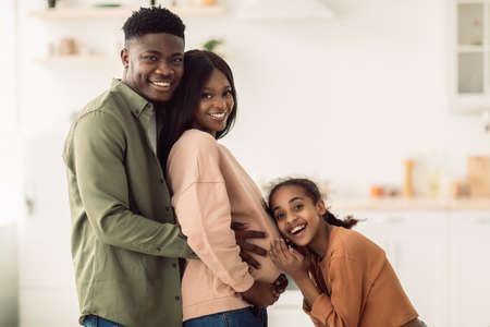Happy African American Family Expecting Baby Standing In Kitchen Indoorの写真素材