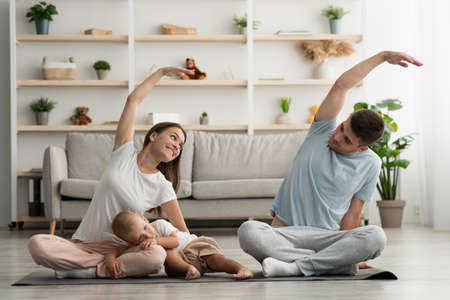 Domestic Trainings. Happy Young Family With Infant Son Doing Sports At Homeの写真素材