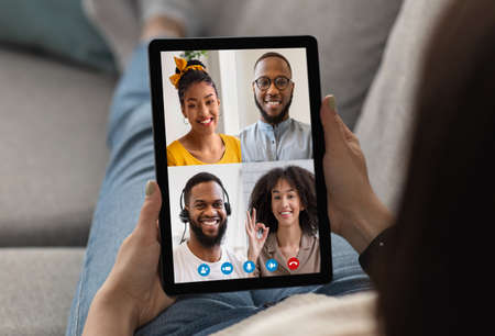 Female holding pad with happy black people faces on screen