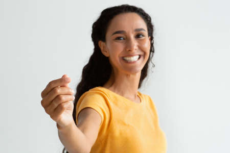 Happy Lady Holding Invisible Object In Hand And Showing It At Camera