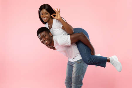 Happy black couple gesturing okay and having funの写真素材