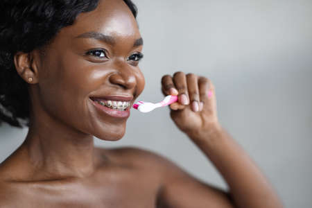 Closeup of young black woman with braces brushing her teethの写真素材