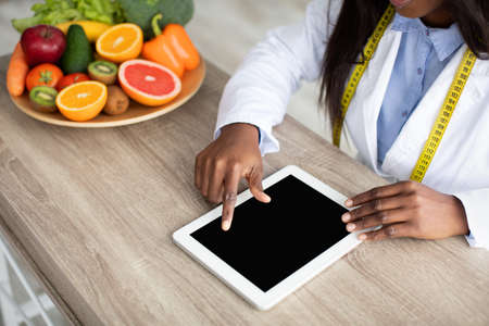 African american female nutritionist working on digital tablet, counting calories or writing diet plan, copy spaceの写真素材