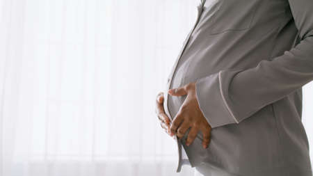 Happy pregnancy concept. Unrecognizable black pregnant woman wearing pajamas hugging her belly,...