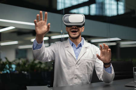 Excited middle eastern doctor in VR glasses, copy space
