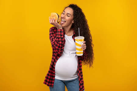 Funny Young Pregnant Lady Holding Burger And Drinkの写真素材