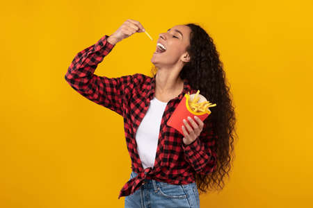 Excited Latin Lady Eating Delicious French Friesの写真素材