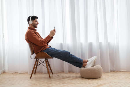 Happy Arab man using cellphone wearing headphonesの写真素材