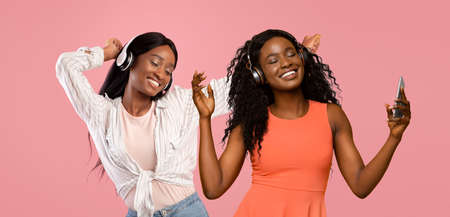 Attractive african american ladies with headsets and smartphone singingの写真素材