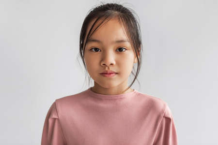 Portrait Of Serious Asian Girl Looking At Camera, Gray Backgroundの写真素材