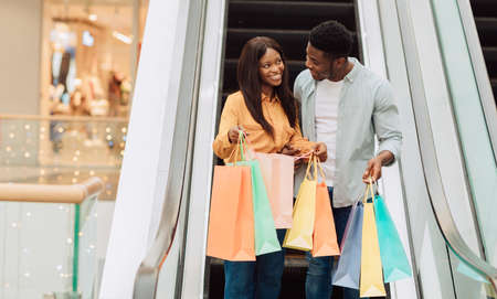 Happy black couple holding shopping bags looking insideの写真素材