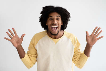 Portrait Of Overjoyed Young African American Guy Raising Hands With Excitementの写真素材