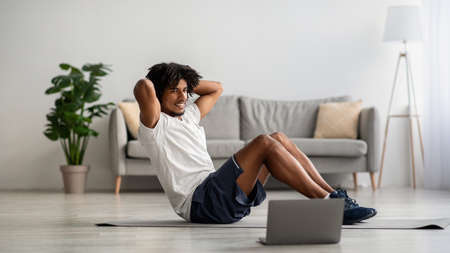 Online Training. Sporty Young Black Male Exercising In Front Of Laptop