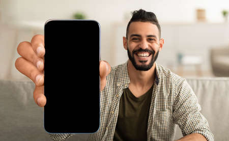Happy arabic guy showing cell phone with empty screen