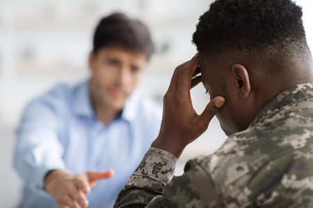 Unrecognizable psychotherapist outstretching hand towards upset soldierの写真素材