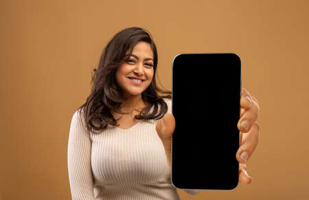 Positive arab lady showing modern smartphone with black empty screen