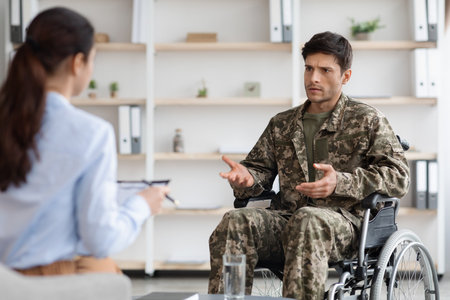 Unhappy disabled young man military veteran attending female psychologistの写真素材