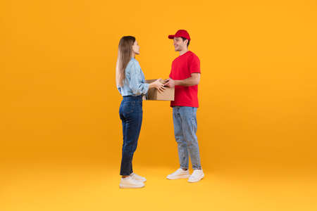 Courier Guy Giving Cardboard Parcel Boxes To Lady, Yellow Backgroundの写真素材