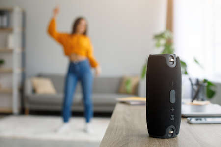 Millennial woman dancing to favorite music at home, selective focus on portable wireless speaker, free spaceの写真素材