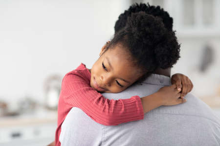 Smiling little black girl hugging her daddyの写真素材