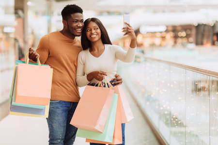 Happy black couple taking selfie at shopping mallの写真素材