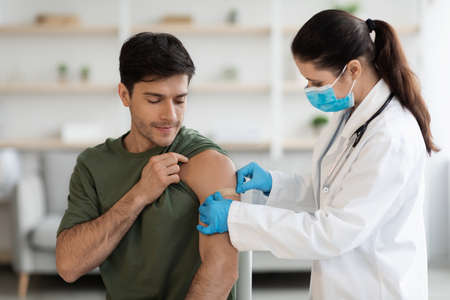 Young soldier getting vaccinated against coronavirus at clinicの写真素材