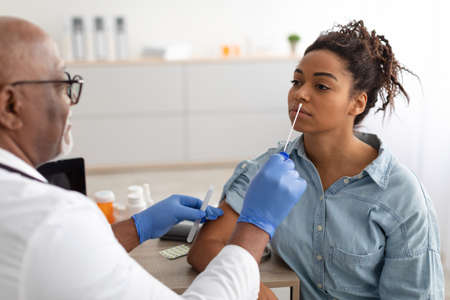 Doctor taking PCR test sample from potentially infected black woman