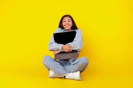 Technology Lover. Excited woman hugging laptop at studioの写真素材