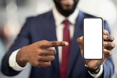 Unrecognizable black businessman pointing at smartphone with empty screenの写真素材