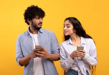 Shocked indian woman spying on her boyfriend using smartphone, texting sms or scrolling social media news feedの写真素材