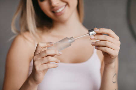 Moisturizing with serum, collagen and hyaluronic acid. Woman with glowing skin holding bottle of essential oil, closeupの写真素材