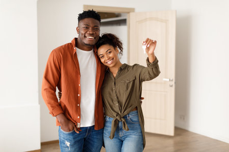 African Spouses Showing House Key Standing Among Moving Boxes Indoorの写真素材