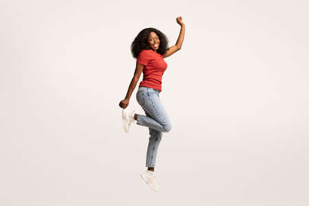 Carefree Young Black Female Jumping In Air And Looking At Camera