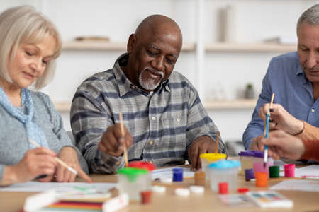 Happy multiracial elderly men and women enjoying painting with brush