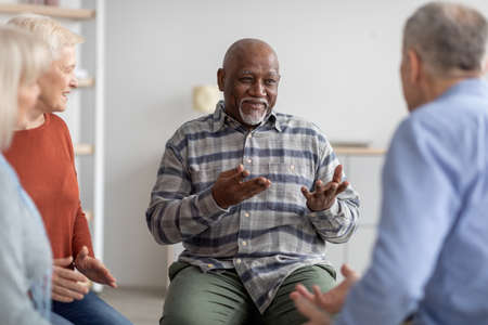 Cheerful african american elderly man having conversation with coachの写真素材