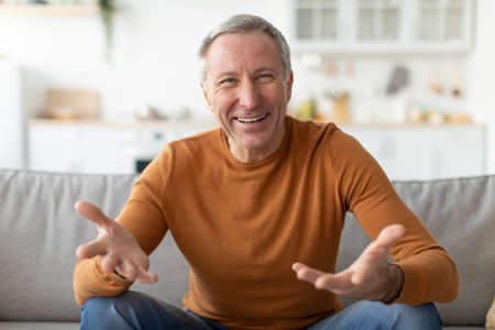 Mature man talking and gesturing to cameraの写真素材