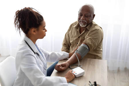 Black female doctor checking measuring pressure on patients handの写真素材