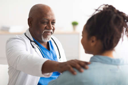Close up of black male doctor tapping patting patients shoulderの写真素材