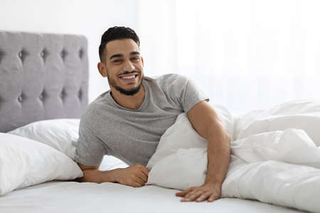 Portrait Of Happy Arab Man Waking Up In Bed In The Morningの写真素材