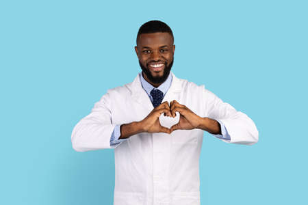 Smiling African American Male Doctor In Uniform Making Heart Sign With Handsの写真素材