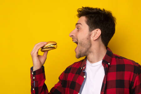 Funny Hungry Guy Holding Burger Biting Sandwich At Studioの写真素材