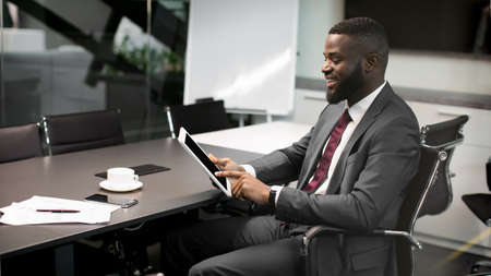 Successful black businessman using digital tablet at office, copy spaceの写真素材